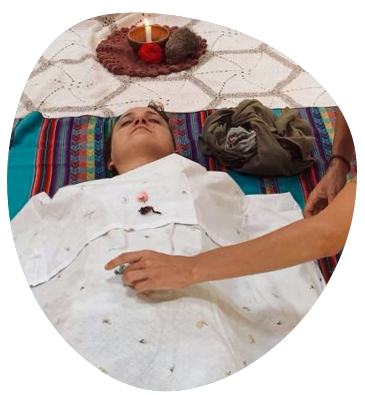 femme couchée sur un tapis, avec une bougie derrière sa tête, et sur elle un drap blanc, en train de se relaxer